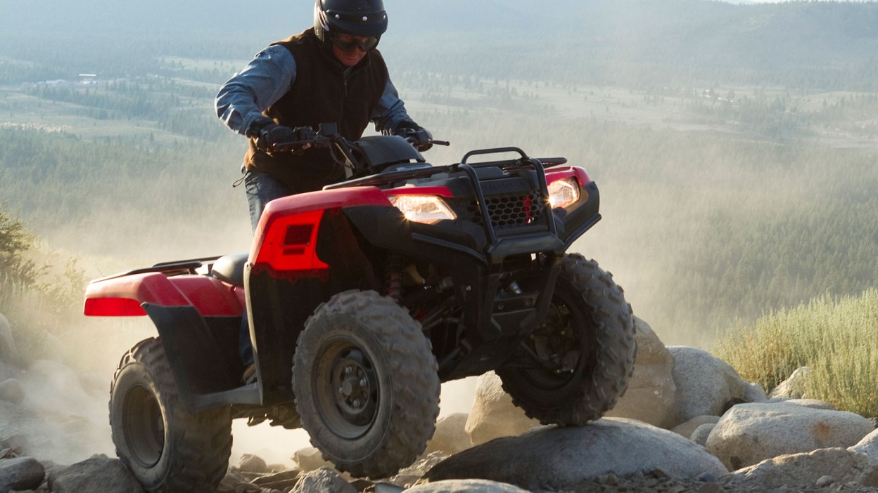 A rider on a Honda Rancher on a rocky trail 