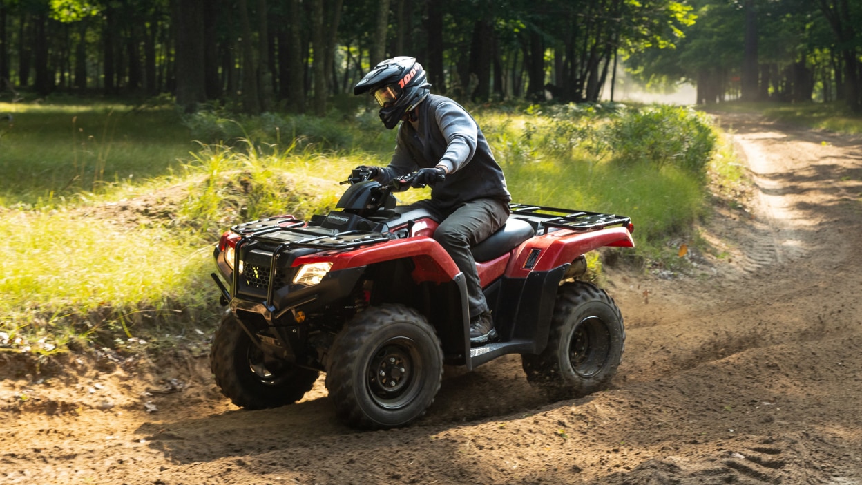 Un conducteur au volant d'un 4x4 tourne à droite sur un chemin de terre. Paysage d'herbe et de bois en arrière-plan.