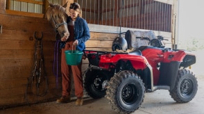 Rear view of Rancher facing the front of a barn. Woman at the rear of Rancher feeding a horse.