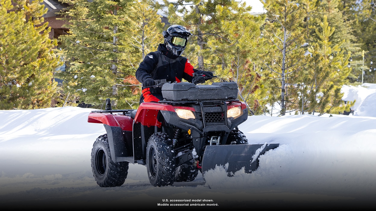 Person riding an ATV with a front cargo box on a snowy trail
