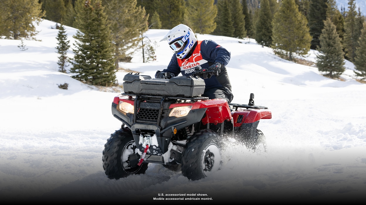 Person riding an ATV with a front cargo box through snow