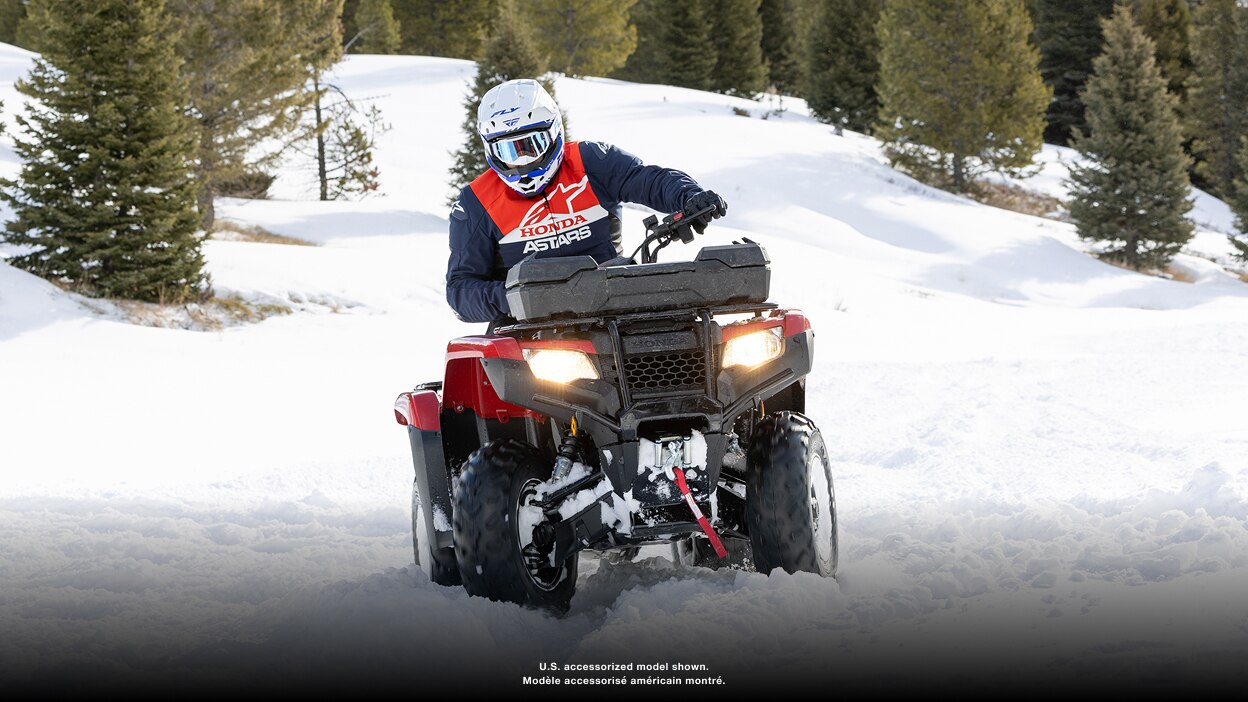 Person riding an ATV with a front cargo box through snow