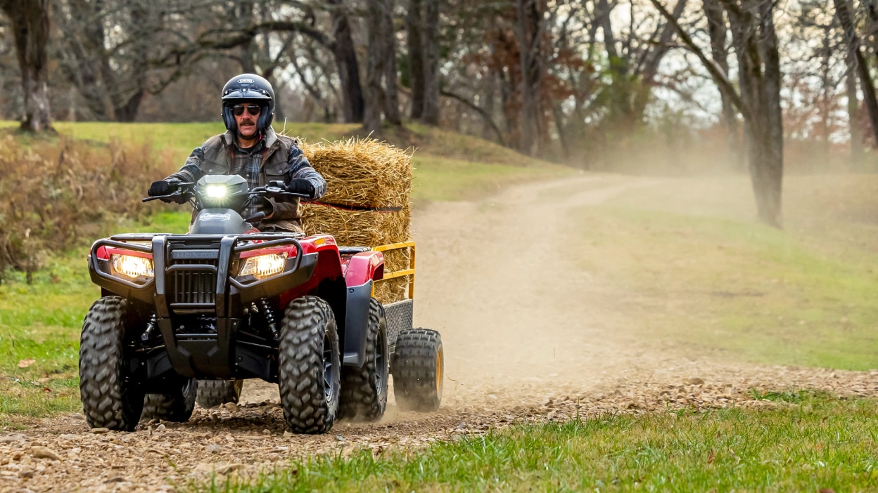 Un pilote sur une Honda Rubicon 700 tirant du foin.