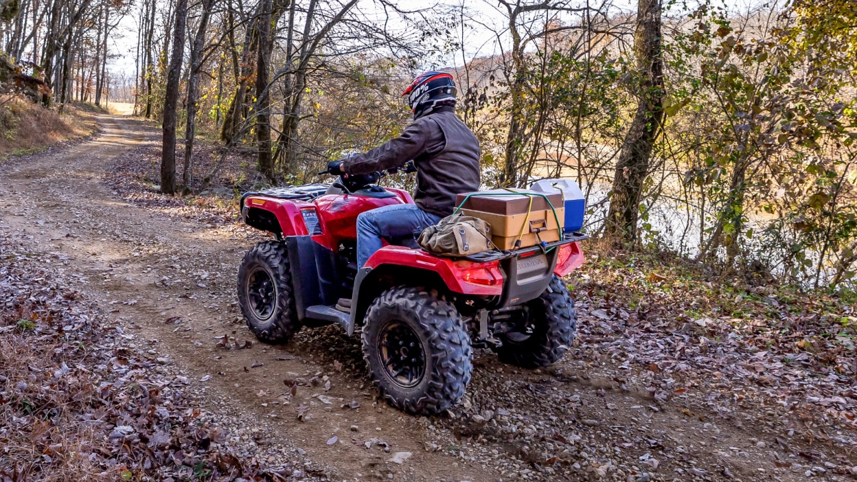 Un pilote sur une Honda Rubicon 700 avec quelques cartons attachés à l'arrière.