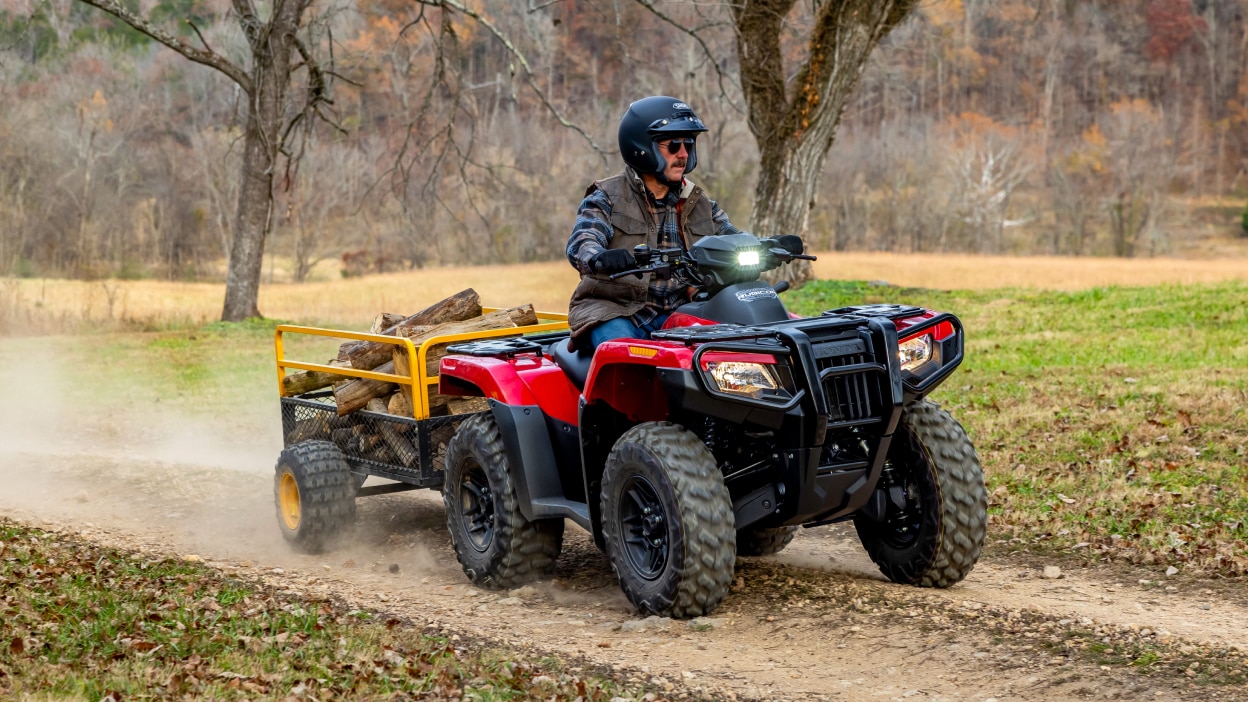 Un pilote transportant du bois dans une remorque sur une Honda Rubicon 700