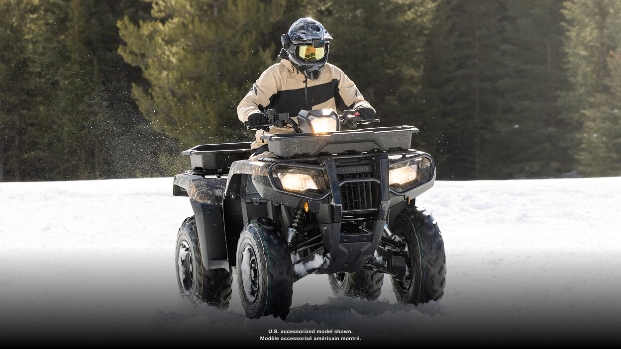 Person driving an ATV towards the camera in snow