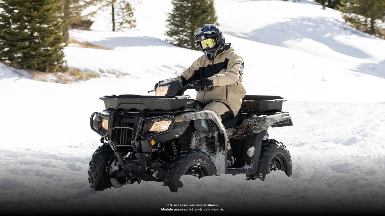 Person driving an ATV in a snowy field