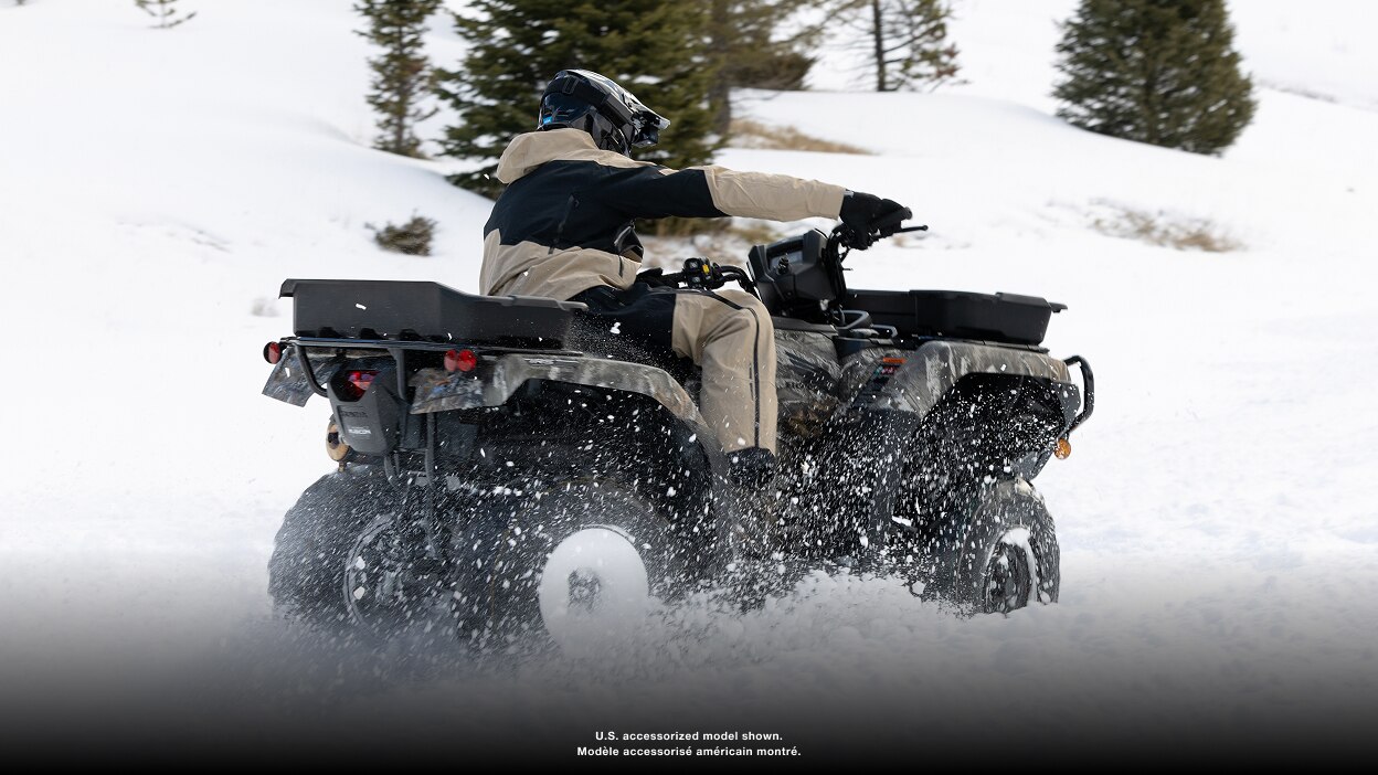 Rear view of an ATV driving on a snowy trail