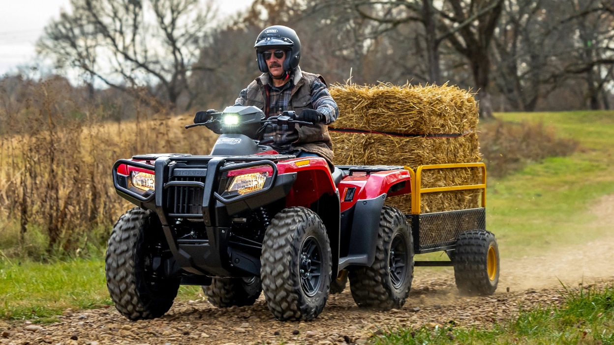 Un homme conduisant un Rubicon 700 avec une remorque rde bottes de foin.
