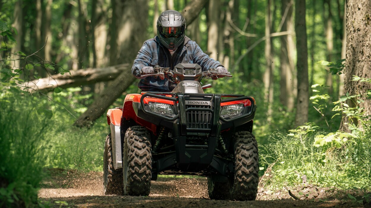 Un homme conduisant un Rubicon 700 sur un sentier en forêt. 