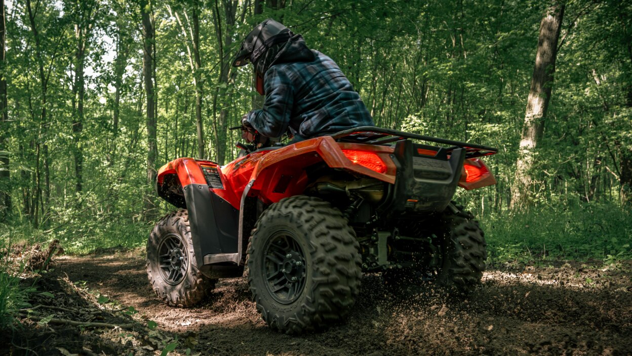 Vue arrière d'un Rubicon 700 en forêt soulevant la poussière. 