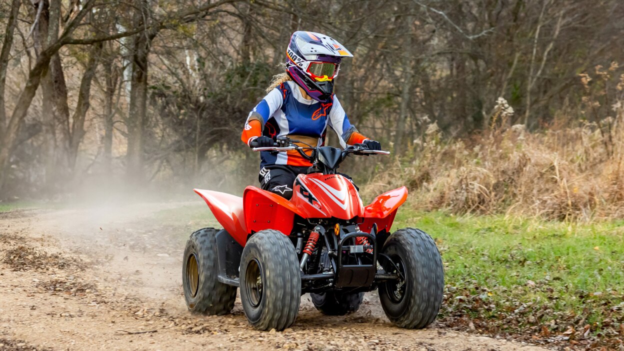 Jeune motard en quad dans les bois. Arbres en arrière-plan.