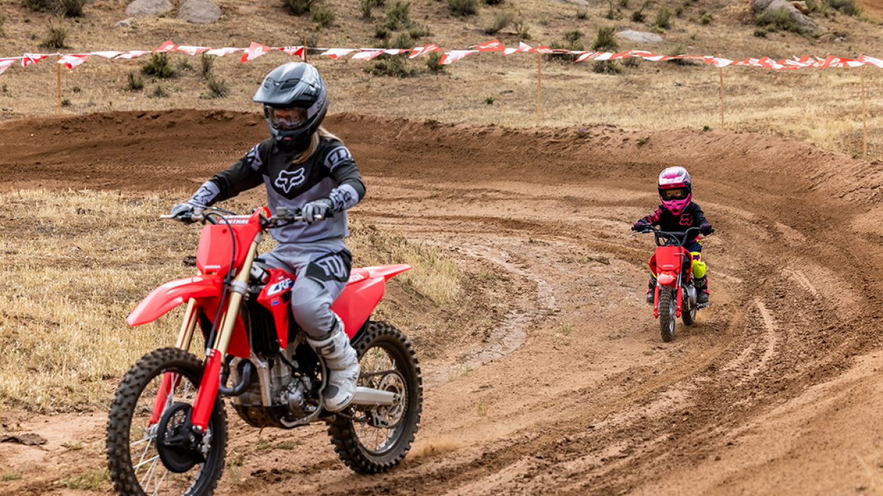 Two riders on a motocross track riding Honda Trail bikes