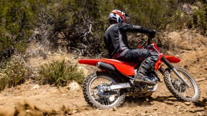 A rider on a Honda Trail motorcycle on a dirt track