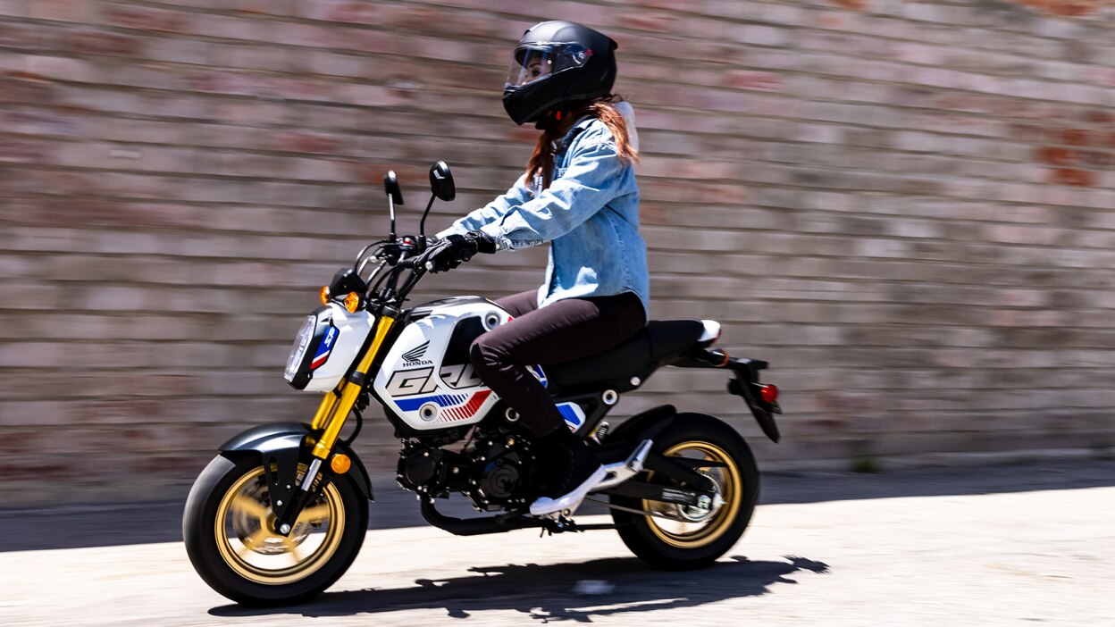 Un cavalier avec une veste en jean bleu clair allant à gauche dans la rue. Mur de briques en arrière-plan.
