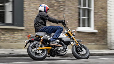 Rider on yellow bike, making left turn on street. Bricked house in background.