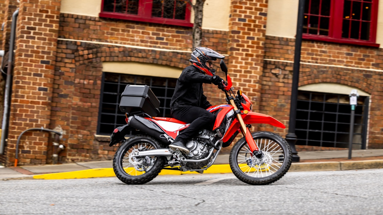 A rider taking a corner on a Dual Sport motorcycle in an urban setting