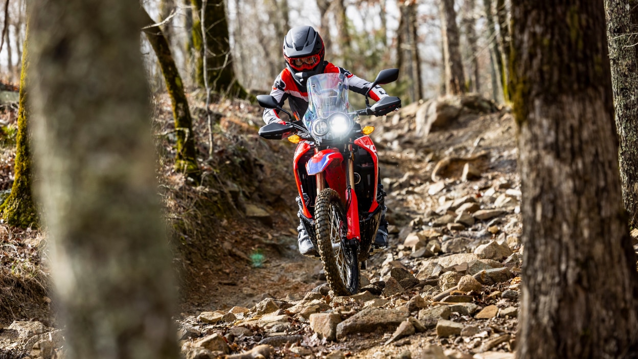 A rider coming down a rocky hill on a Honda Dual Sport motorcycle