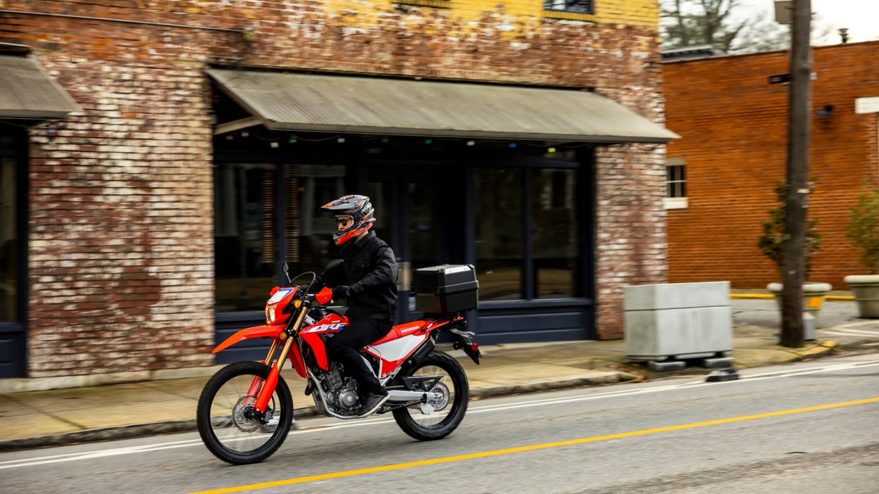 A rider on a Honda Dual Sport motorcycle on an urban road
