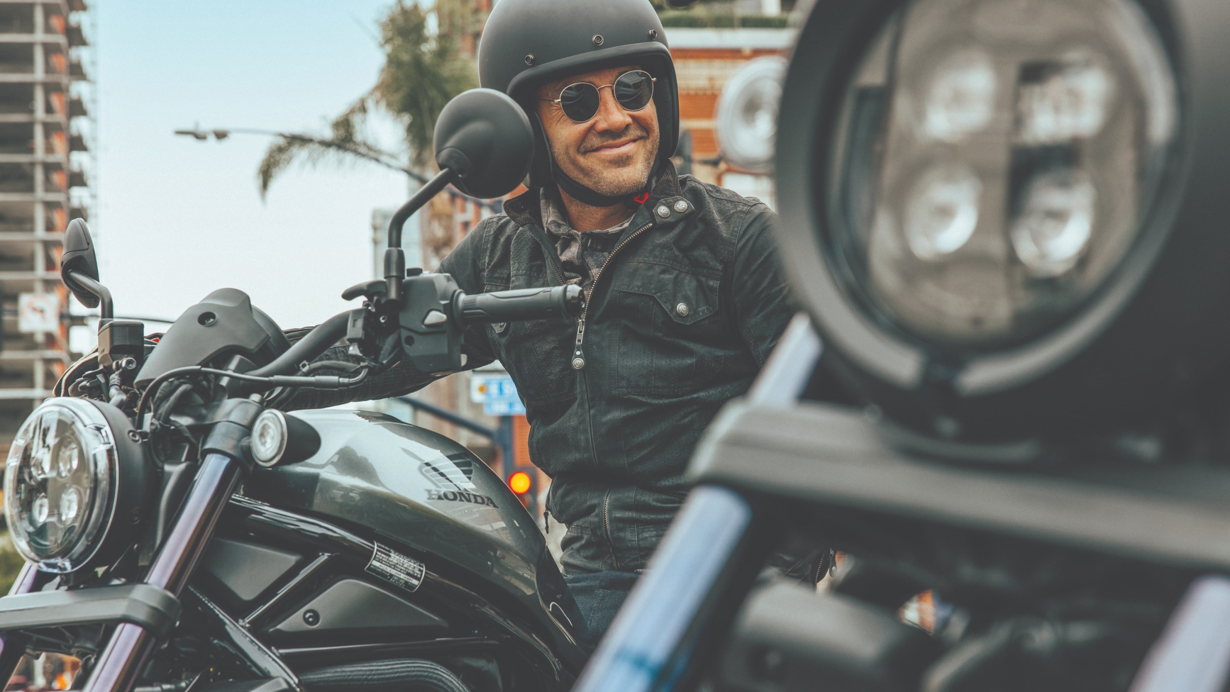 A rider wearing a black helmet smiling on a Honda Rebel 