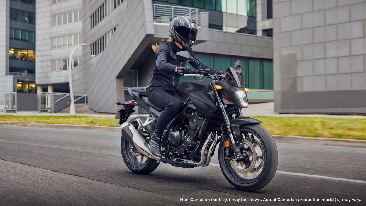 A rider on a CB500F in an urban landscape, Non Canadian model may be shown 
