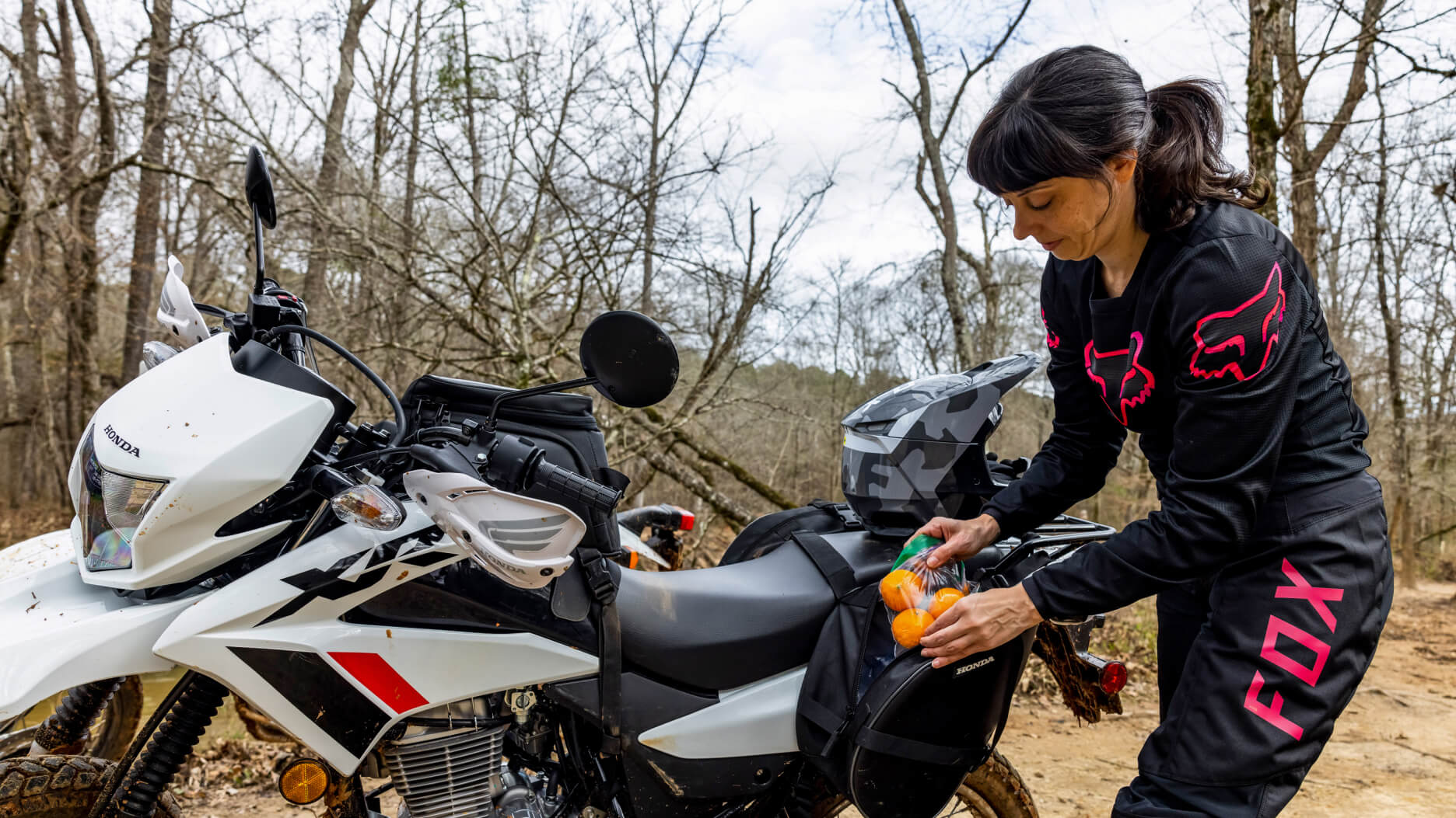 A rider beside a Honda XR150L putting some snacks in her bag