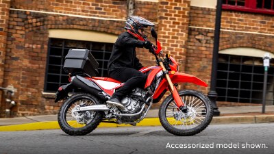 A side angle view of a person riding the Honda CRF300L on a city street