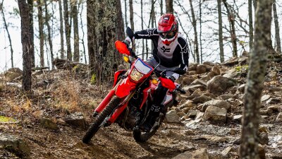 A front angle view of a person riding the Honda CRF300L in the forest