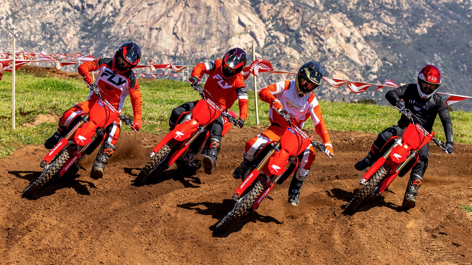 Four riders turning left on dirt track. Front facing.