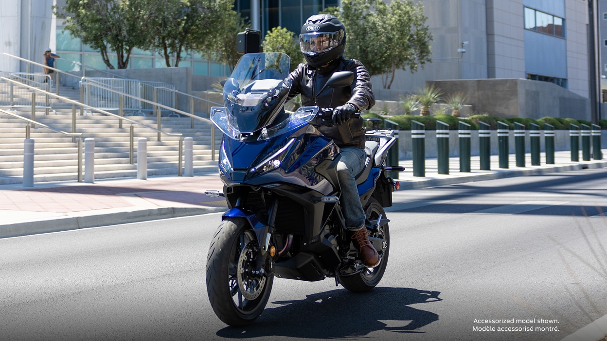 Un motard tourné vers la gauche sur la NT1100. Paysage urbain en arrière-plan.