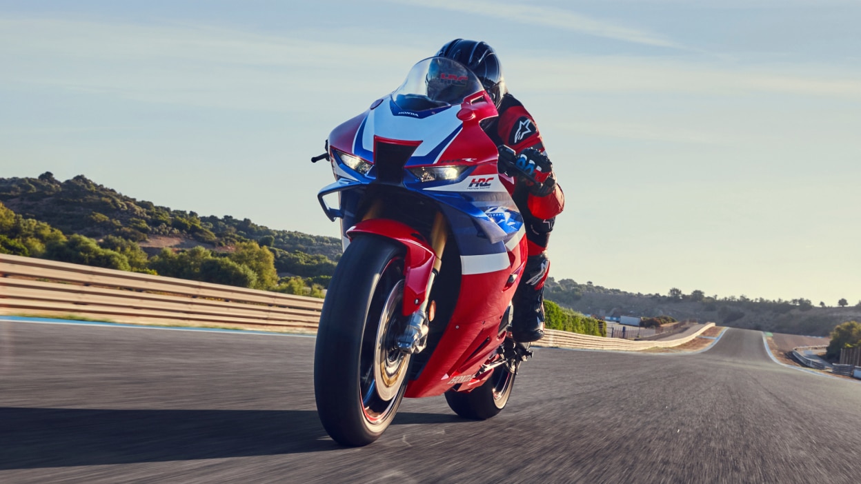 Pilote sur CBR1000RR-R FIREBLADE SP allant à gauche sur la piste. La lumière du soleil en arrière-plan.