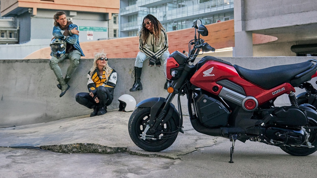 Navi on stand. In background, two people sitting on wall, one person leaning against wall.
