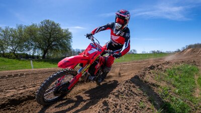 Pilote de motocross conduisant une moto tout-terrain Honda rouge sur une piste de terre