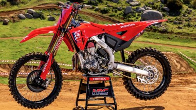 Moto tout-terrain Honda CRF450RWE rouge stationnée sur un trépied à l'extérieur