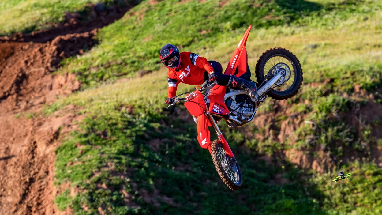 Rider mid air on motorbike. Green field in background.