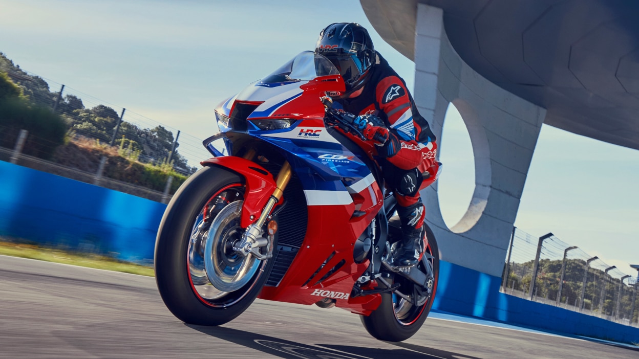 Un motard sur une CBR1000RR-R Fireblade sur circuit. Un pont est visible en arrière-plan.