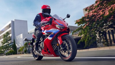 Un motard sur une CBR650R à embrayage électronique roule à droite. Paysage urbain en arrière-plan.