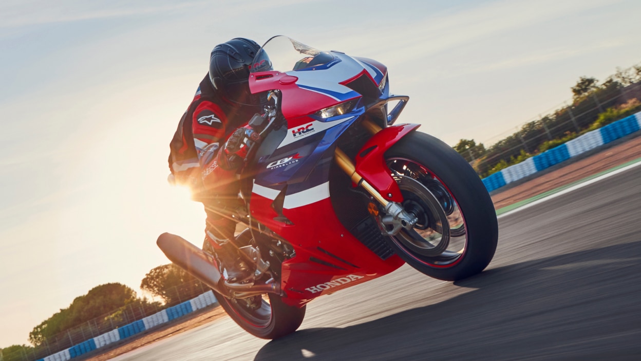 Rider on CBR1000RR-R Fireblade on race track. Blue sky in background.