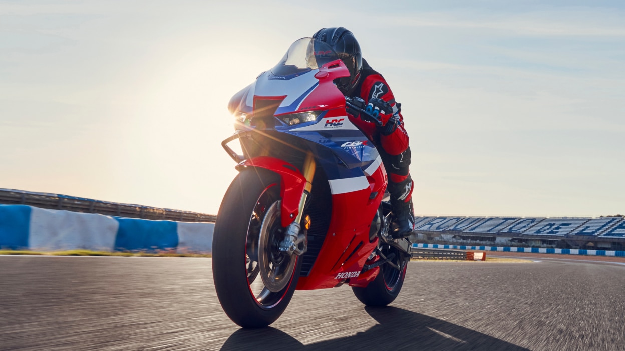 Rider on CBR1000RR-R Fireblade on race track. Blue sky in background.