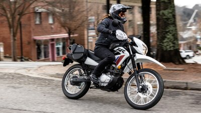 Un motard sur une XR150L tourne à gauche dans la rue.