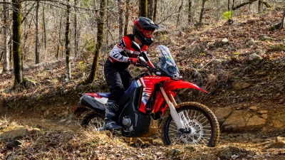 Pilote sur CRF450L descendant une piste en terre.