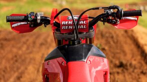 The clutch on the handlebars of a parked CRF450RX on a trail