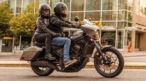 Two riders going right on street. Glass buildings in background. Accessorized model shown.