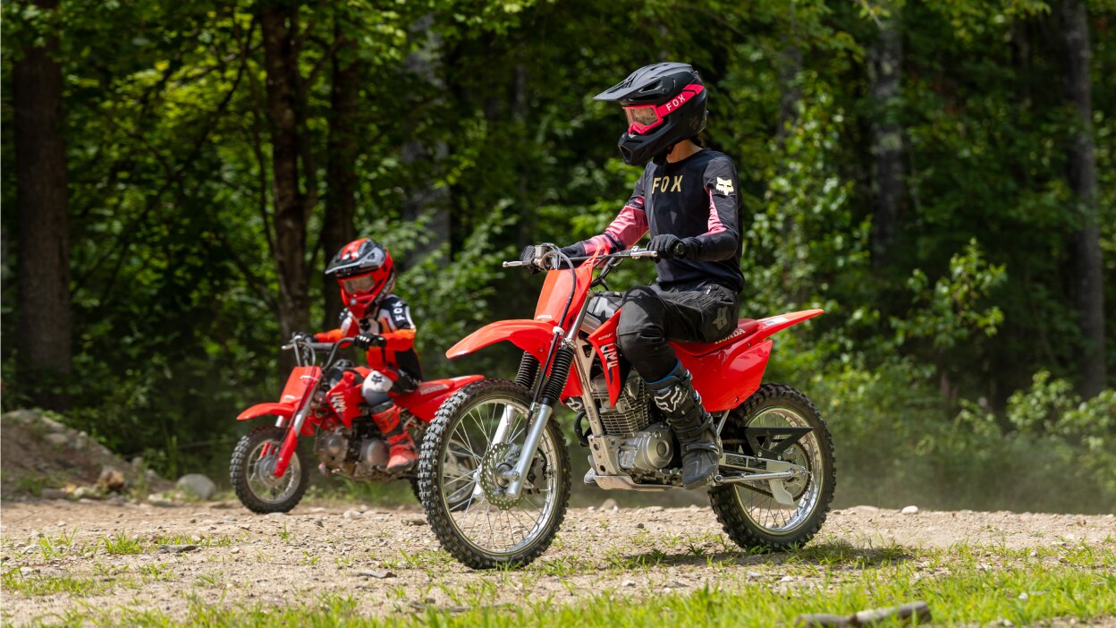 A side profile of a rider stopped on a dirt path under a tree canopy.