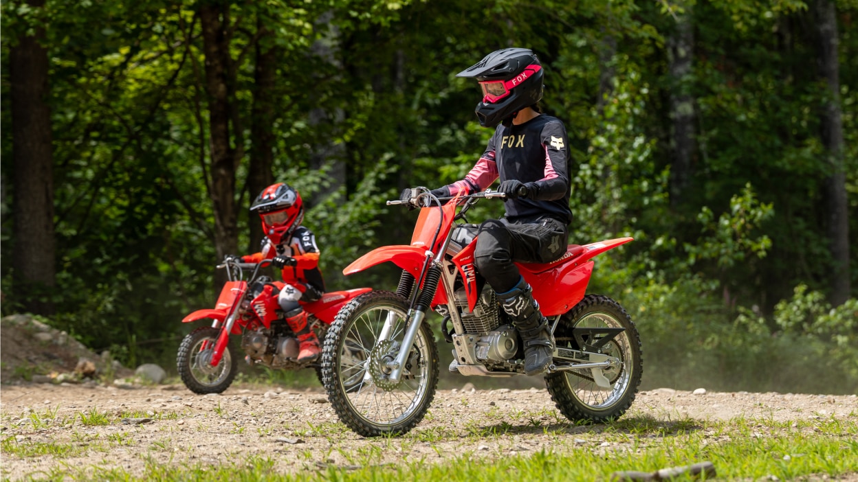 A side profile of a rider stopped on a dirt path under a tree canopy.