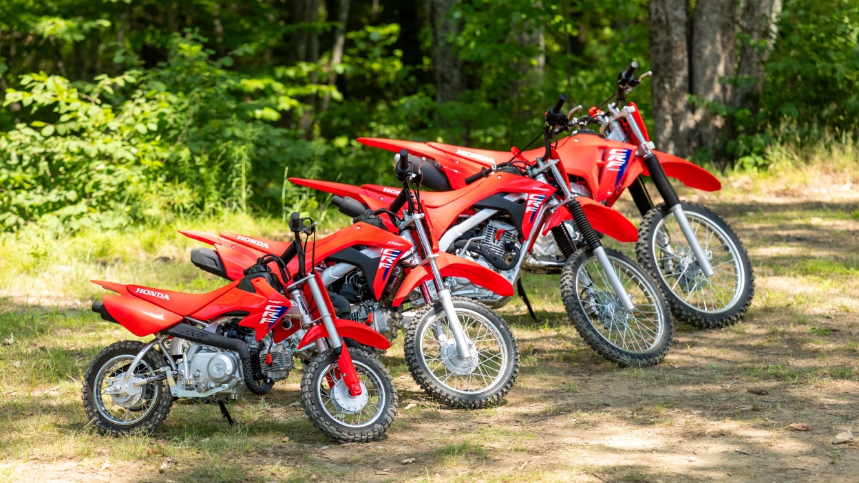A single rider on a red dirt bike kicking up dust on a trail.