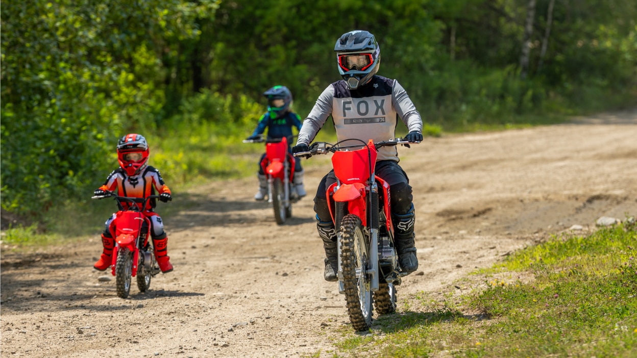 A group of five riders parked in a row on a wooded trail.