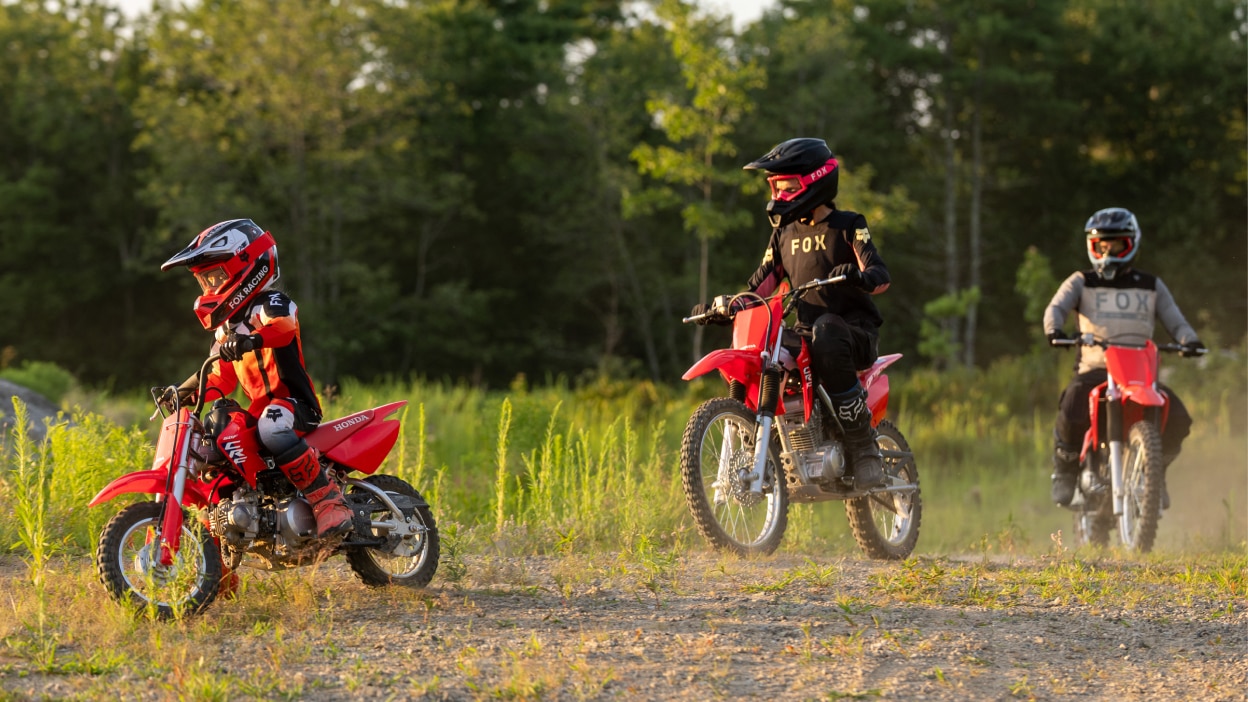 Plusieurs motocyclistes positionnés sur un large sentier de terre.