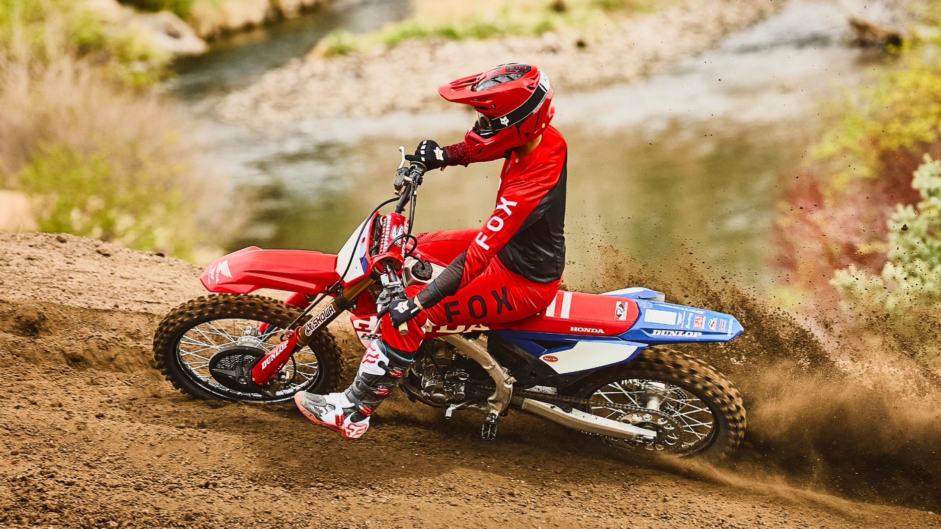 Motocross rider in red gear jumping a red dirt bike.