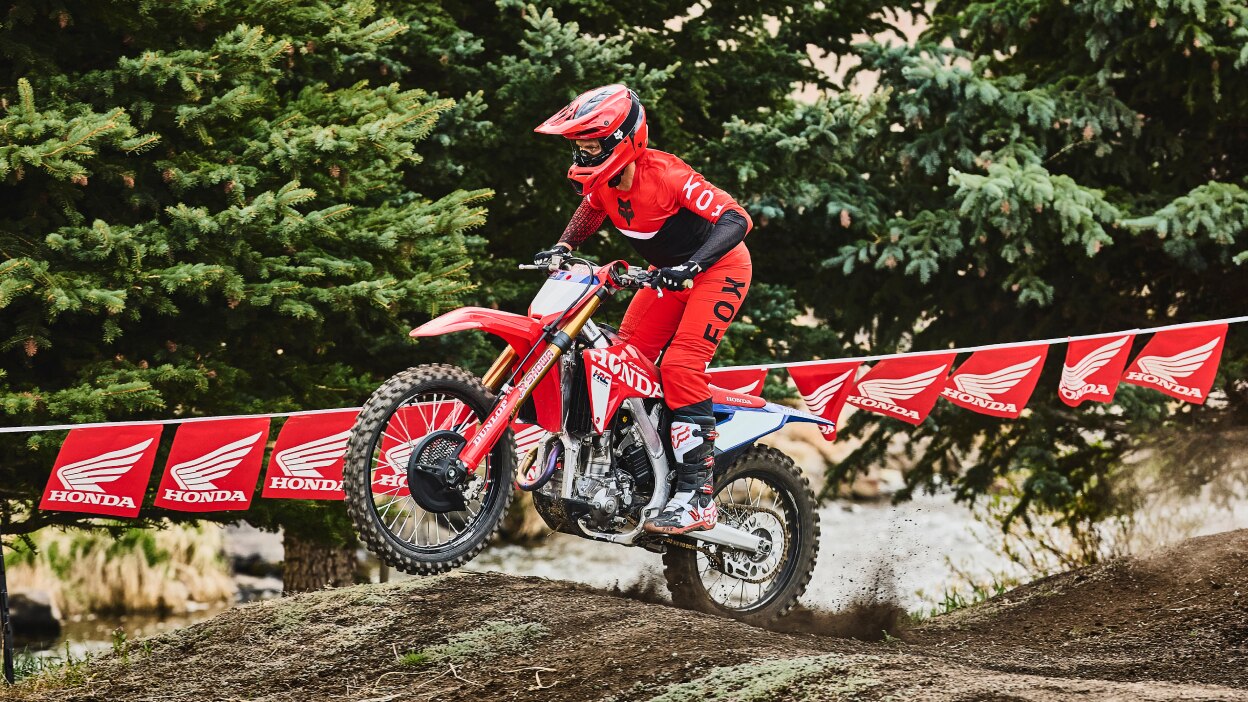 Motocross rider in red gear accelerating on a red dirt bike.